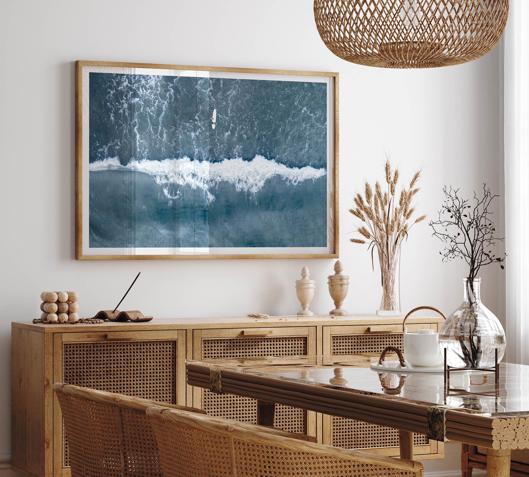 Aerial ocean wall art featuring a lone surfer and a breaking white wave in the deep blue waters of Hanalei Bay.