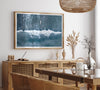 Aerial ocean wall art featuring a lone surfer and a breaking white wave in the deep blue waters of Hanalei Bay.
