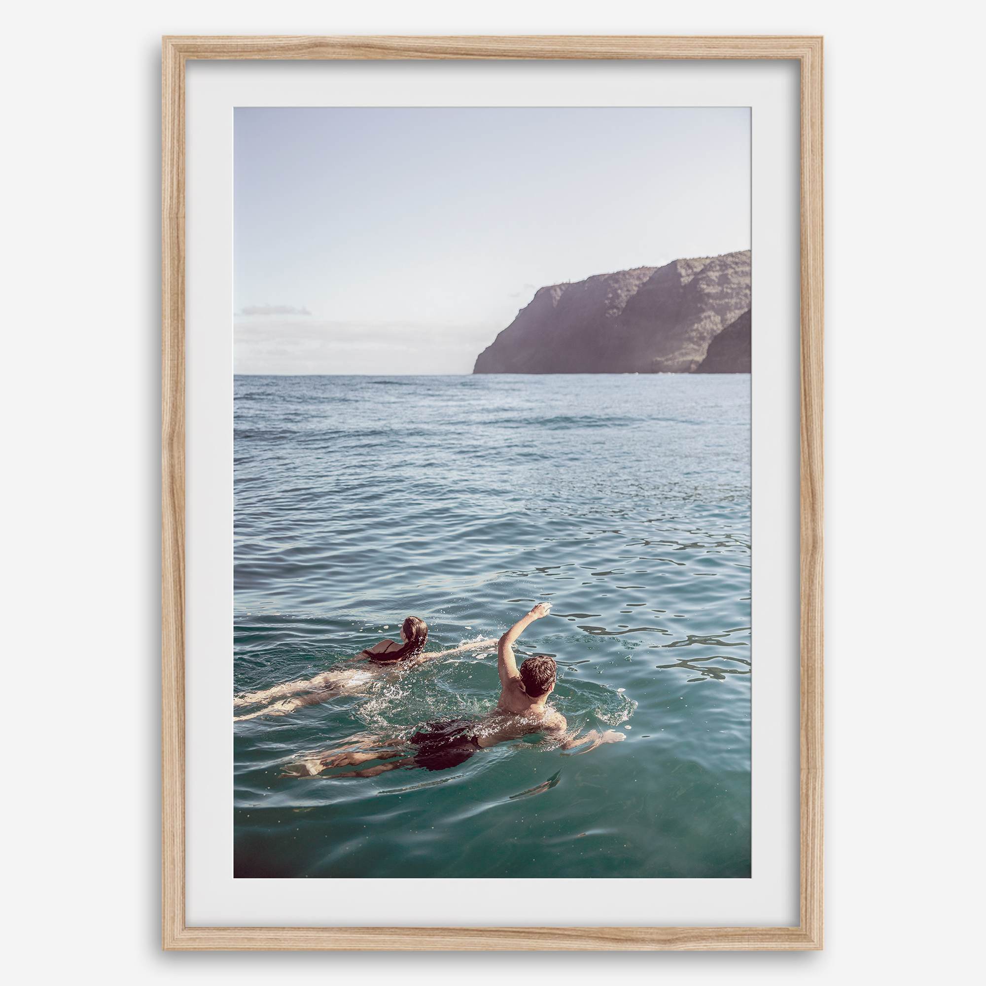 Summer wall art of a coastal Hawaiian landscape with figures swimming in deep blue ocean water.