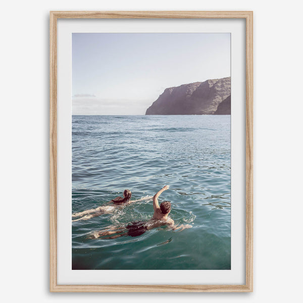 Summer wall art of a coastal Hawaiian landscape with figures swimming in deep blue ocean water.