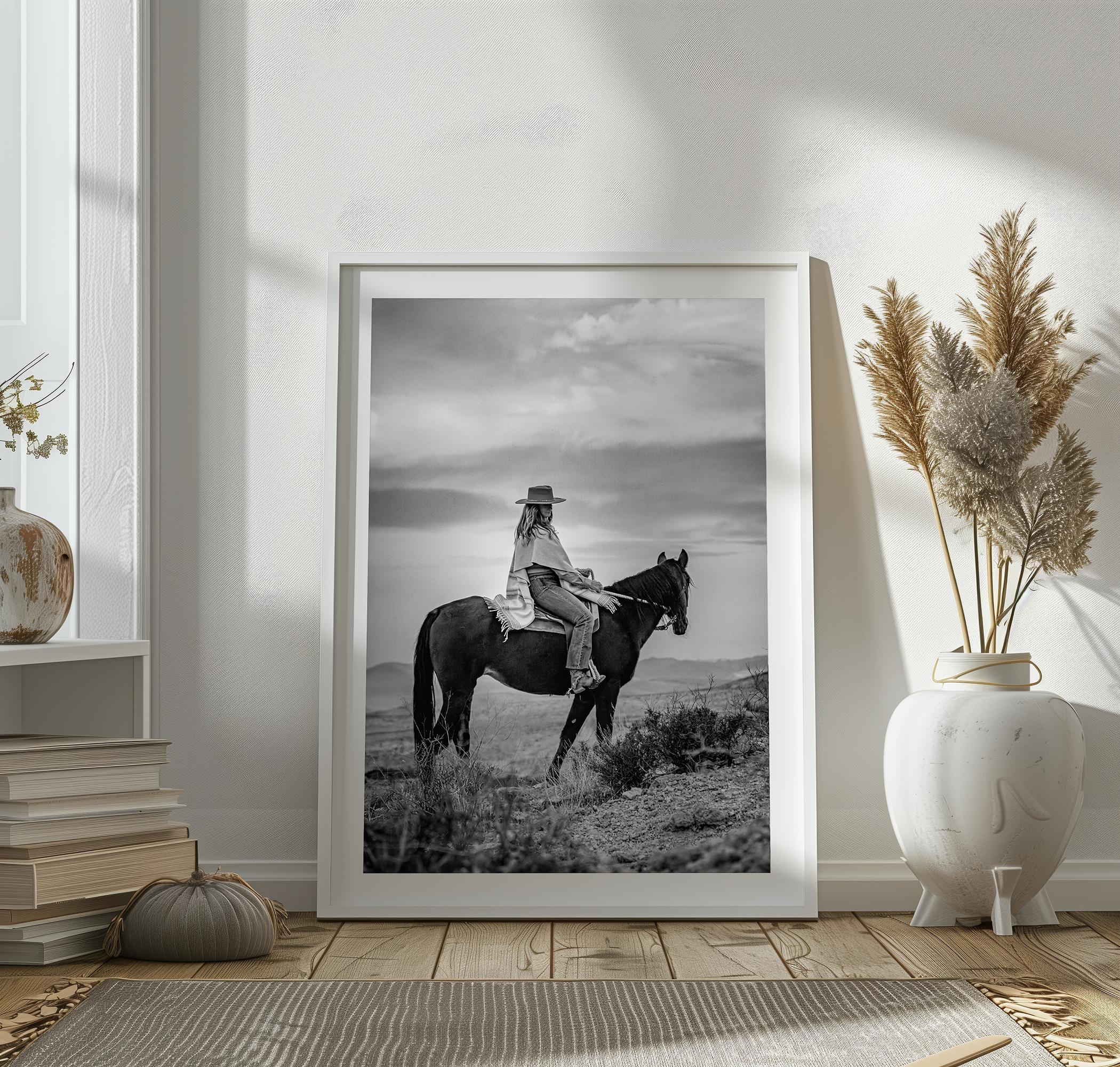 A black and white western rustic wall art - Cowgirl on horseback at sunset in desert landscape