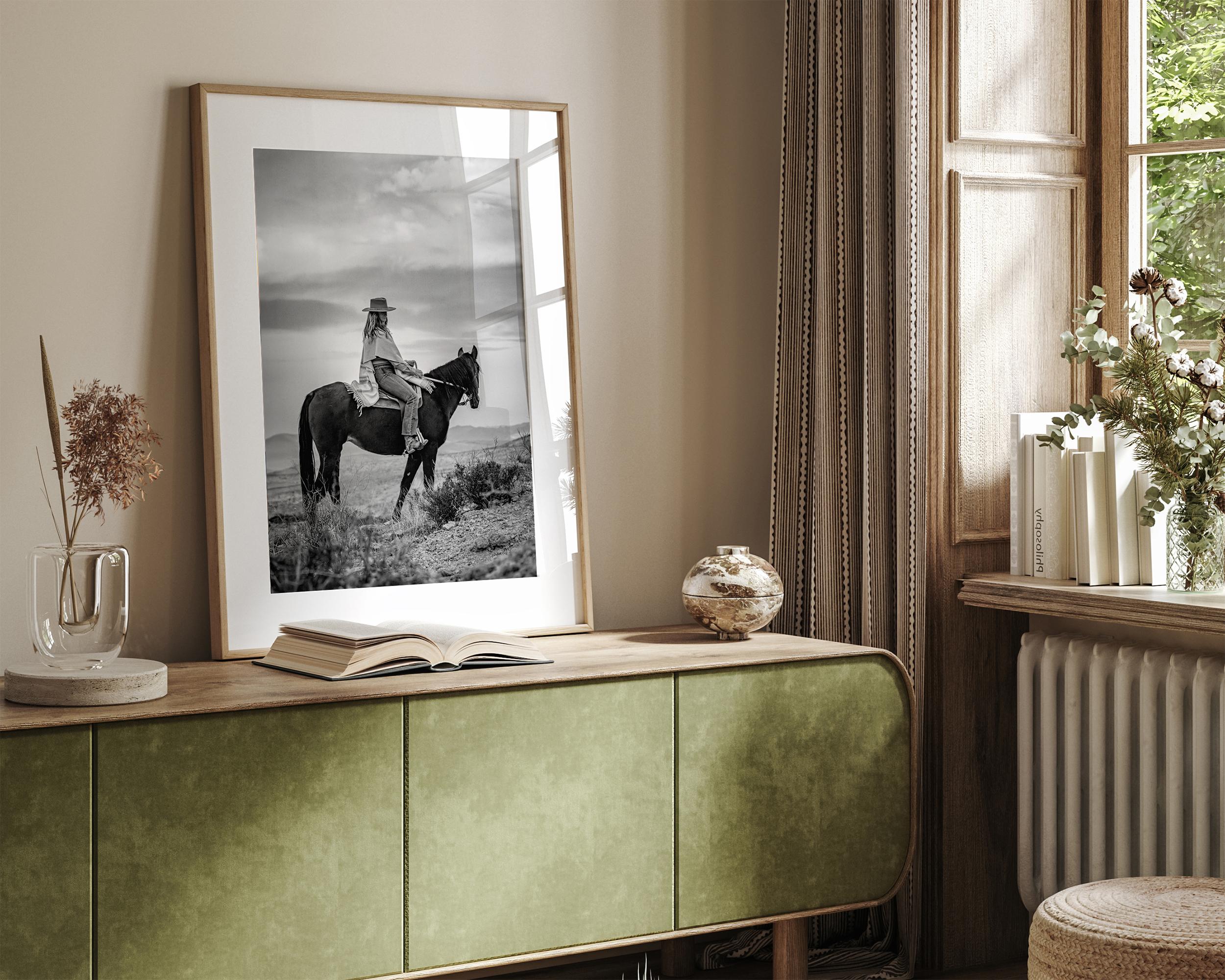 A black and white western rustic wall art - Cowgirl on horseback at sunset in desert landscape