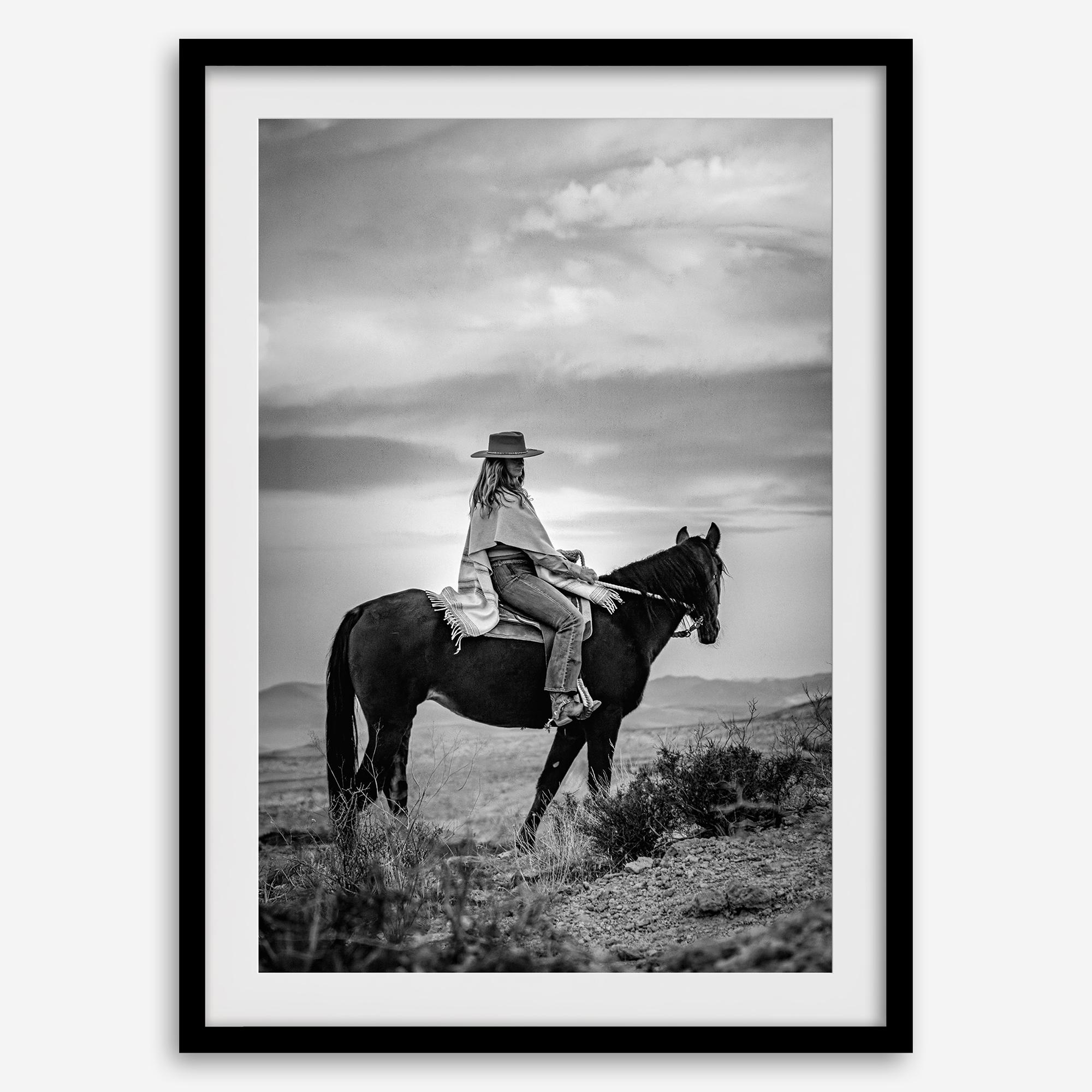 A black and white western rustic wall art - Cowgirl on horseback at sunset in desert landscape