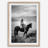 A black and white western rustic wall art - Cowgirl on horseback at sunset in desert landscape