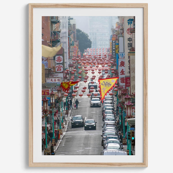 Red lanterns line Grant Avenue in San Francisco’s Chinatown, framed by colorful signs and bustling city life. Available as a framed or unframed print.