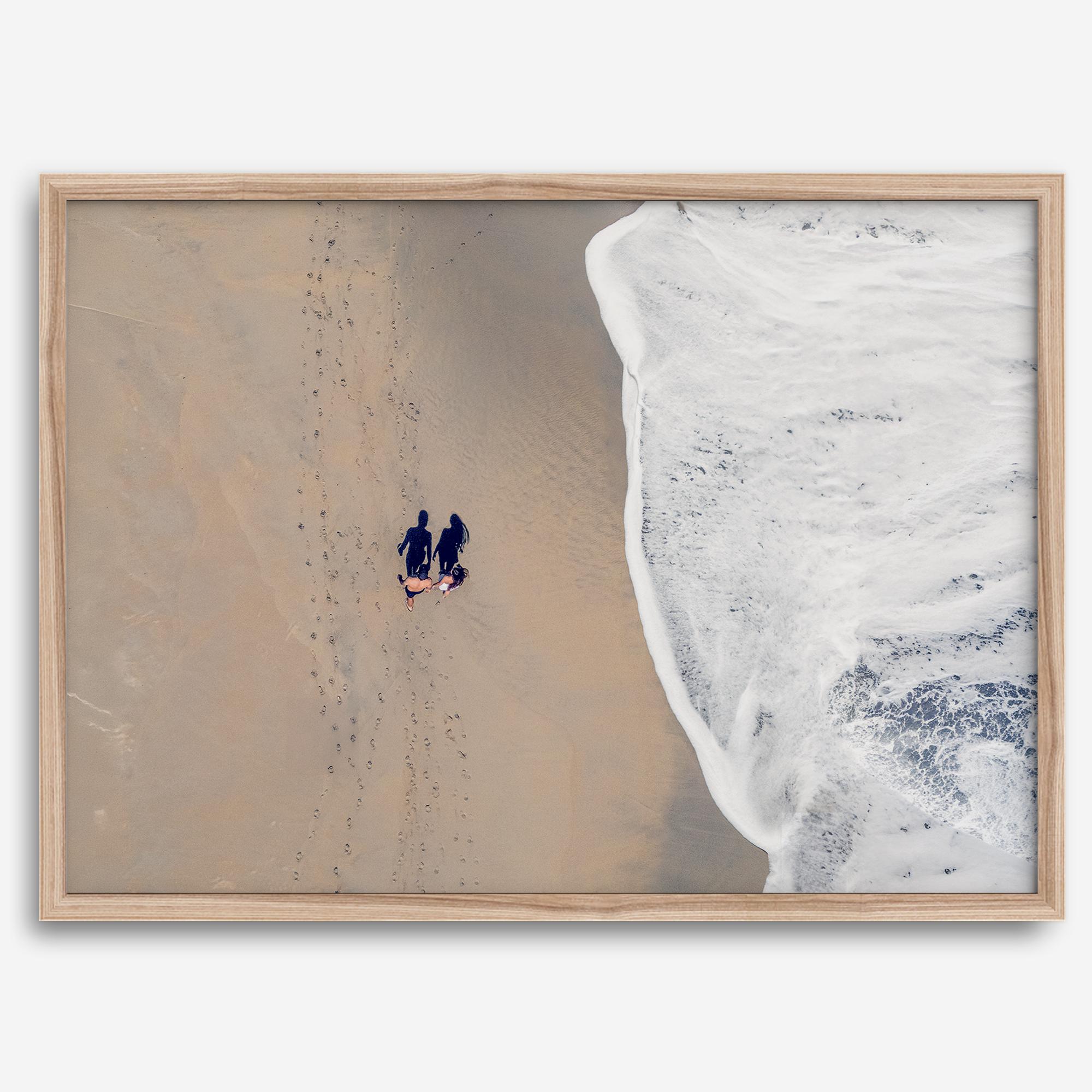 Aerial beach photograph of a couple beside Pacific Ocean waves in Capitola, California, styled as romantic coastal bedroom wall art.