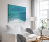 Aerial ocean canvas print showing a lone surfer paddling through turquoise waves with white surf along the beach shoreline