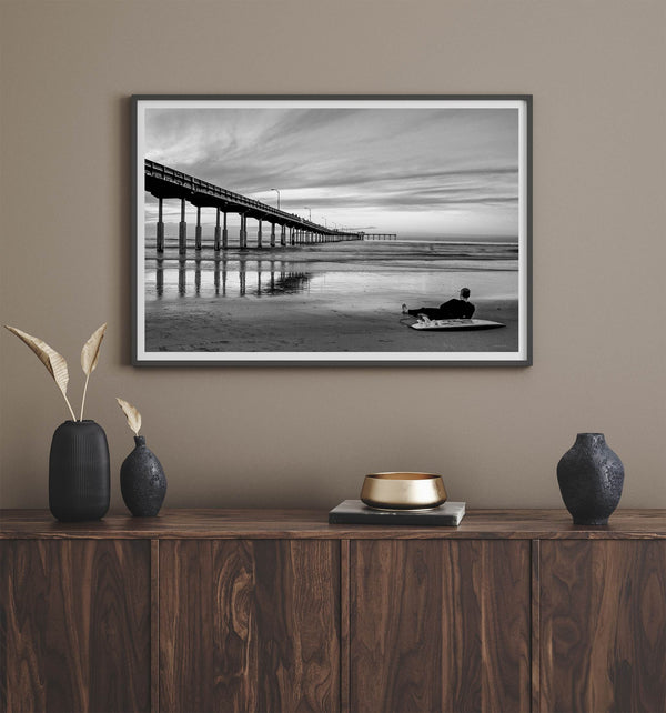 Ocean Beach Pier San Diego photographed in black and white with a lone surfer resting on the shoreline.