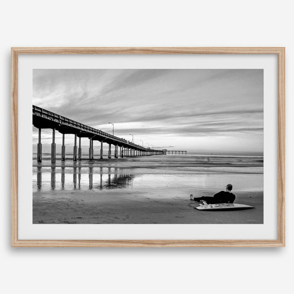 Ocean Beach Pier San Diego photographed in black and white with a lone surfer resting on the shoreline.