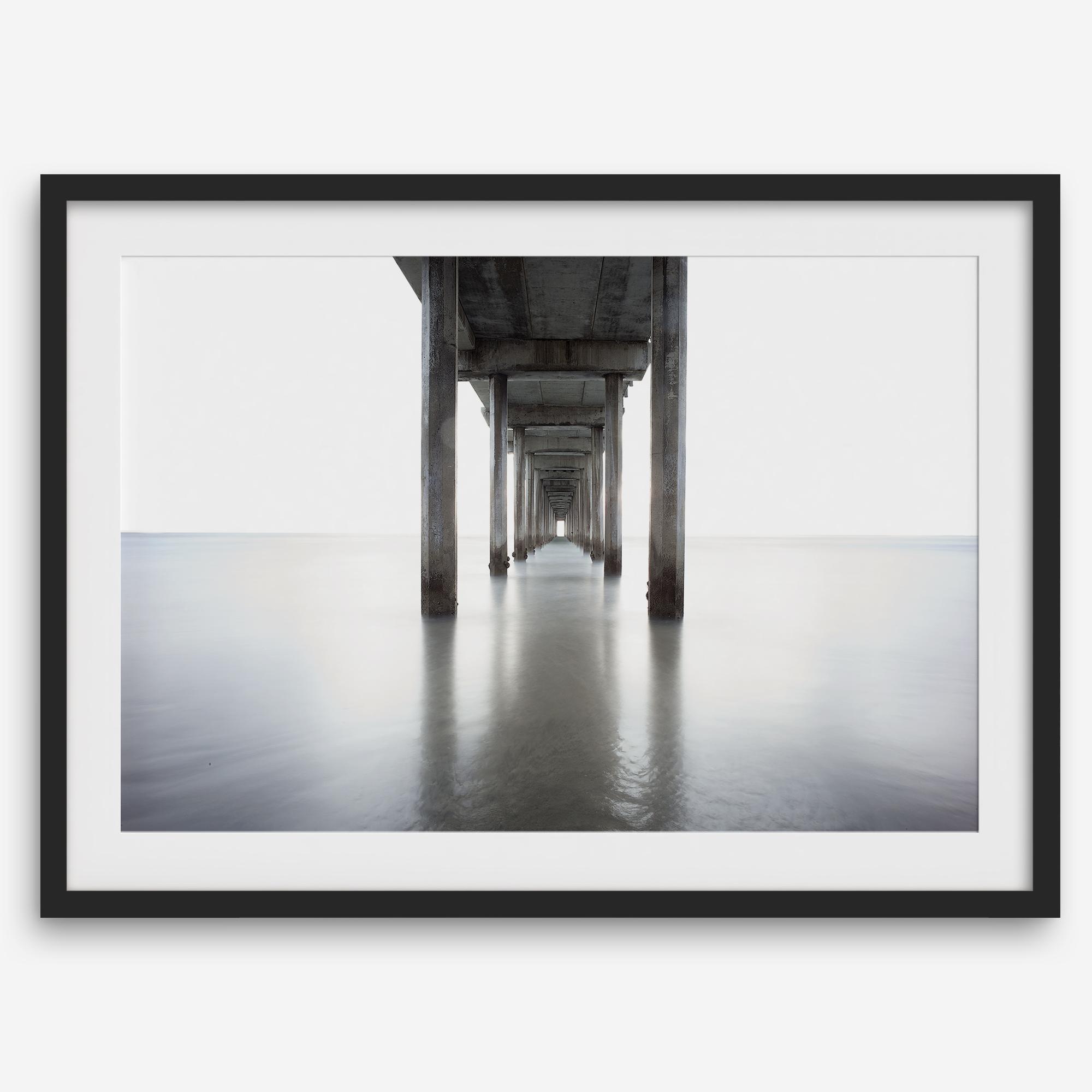 La Jolla coastal photograph looking beneath Scripps Pier toward the Pacific horizon, featuring symmetrical columns and minimalist ocean tones.