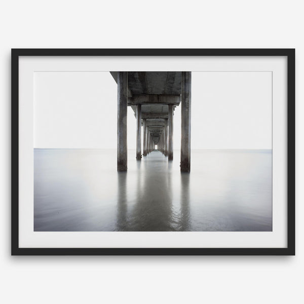 La Jolla coastal photograph looking beneath Scripps Pier toward the Pacific horizon, featuring symmetrical columns and minimalist ocean tones.