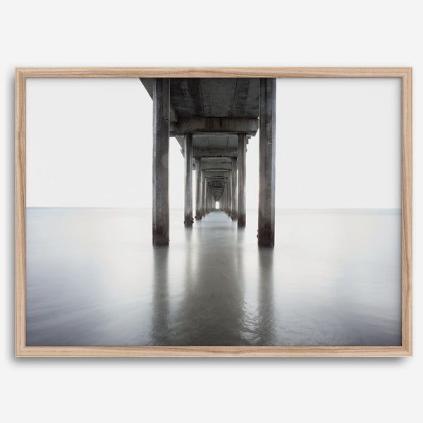La Jolla coastal photograph looking beneath Scripps Pier toward the Pacific horizon, featuring symmetrical columns and minimalist ocean tones.
