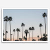 Silhouetted palm trees in Palm Springs under a clear blue sky with pink desert mountains in background