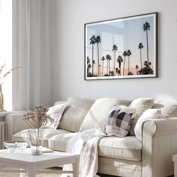 Silhouetted palm trees in Palm Springs under a clear blue sky with pink desert mountains in background