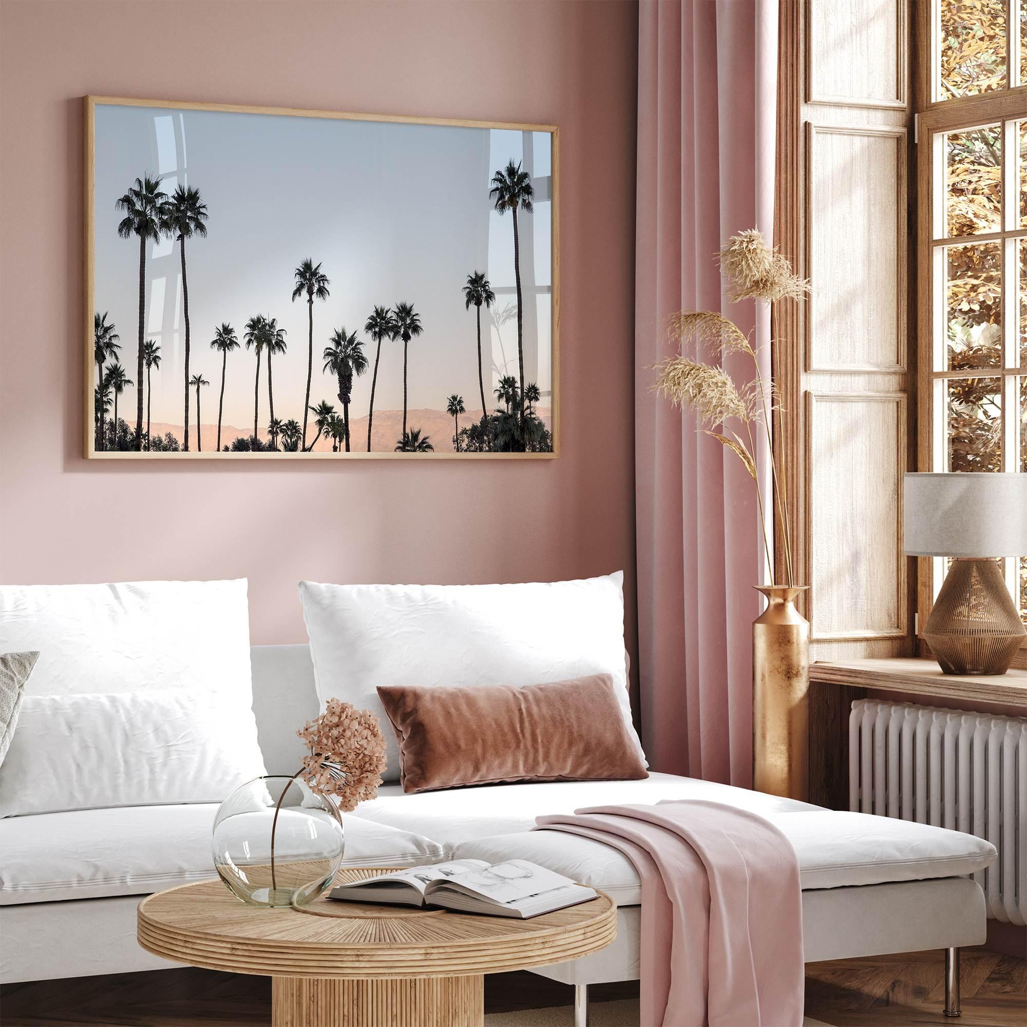 Silhouetted palm trees in Palm Springs under a clear blue sky with pink desert mountains in background