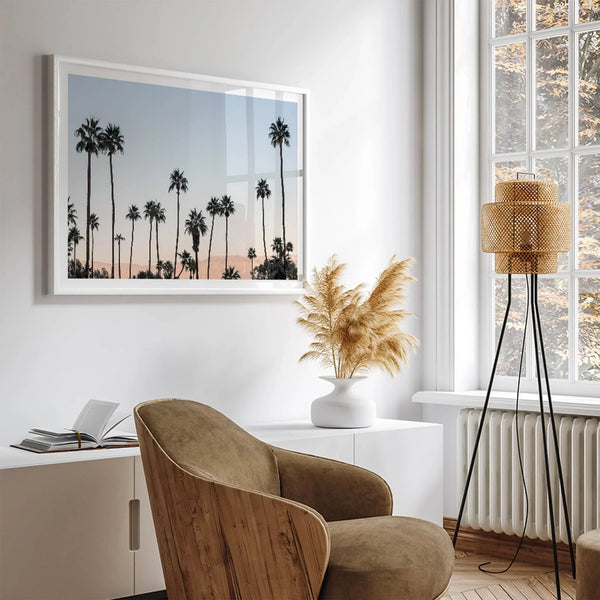 Silhouetted palm trees in Palm Springs under a clear blue sky with pink desert mountains in background