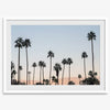 Silhouetted palm trees in Palm Springs under a clear blue sky with pink desert mountains in background