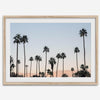 Silhouetted palm trees in Palm Springs under a clear blue sky with pink desert mountains in background