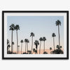 Silhouetted palm trees in Palm Springs under a clear blue sky with pink desert mountains in background
