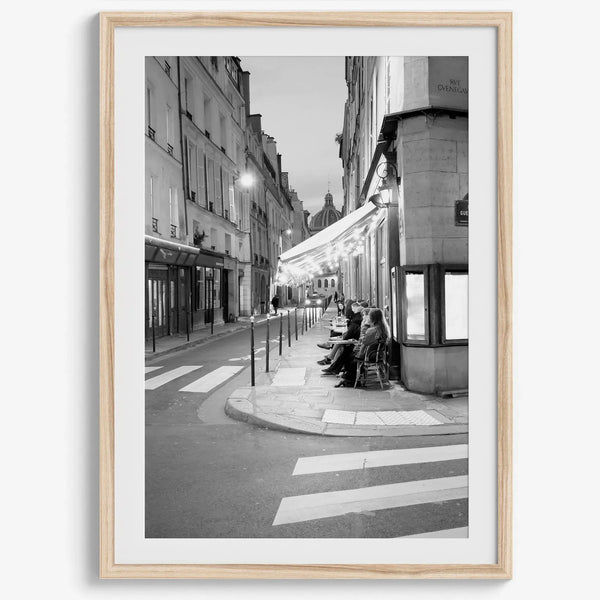 Paris street photography showing glowing café at dusk on Rue de l’Université in black and white.