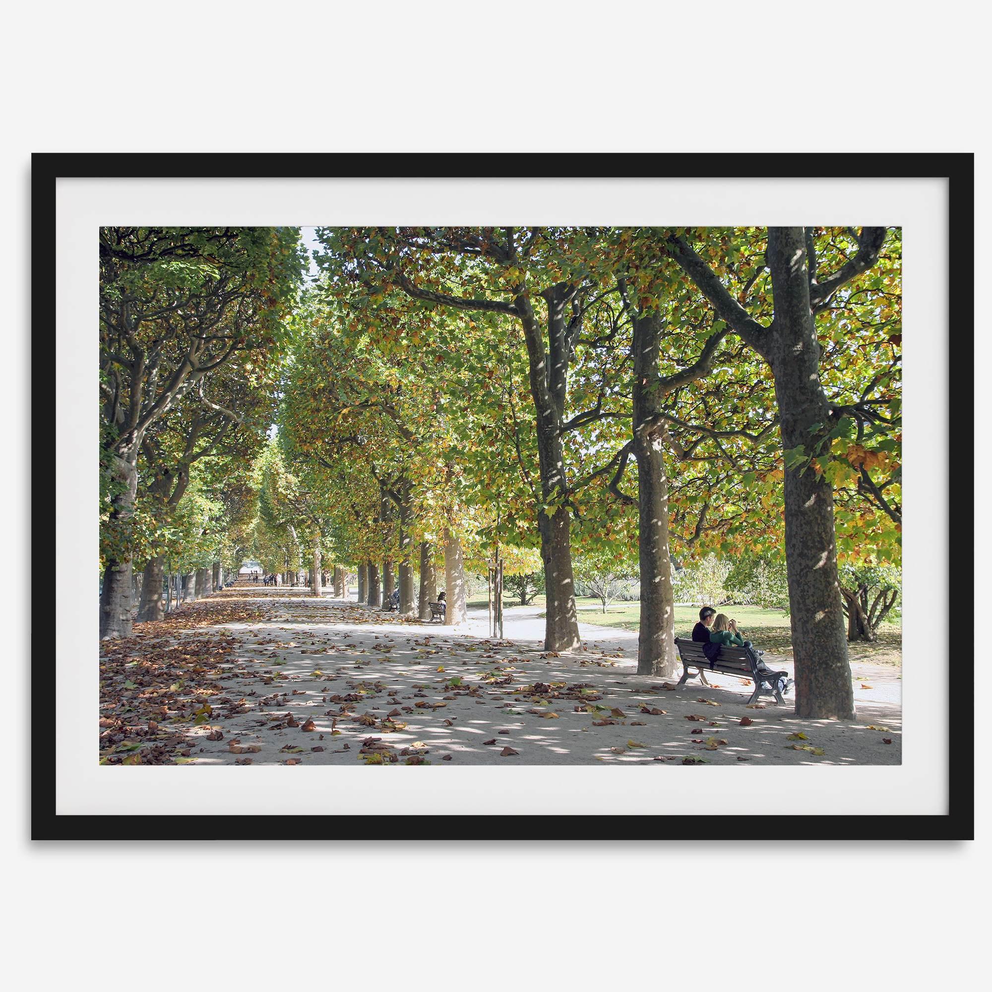 A fine art Paris print of Jardin des Tuileries in fall, featuring a couple sitting on a bench beneath vibrant autumn trees, surrounded by golden foliage.