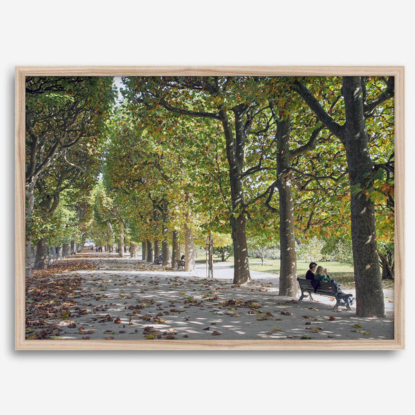 A fine art Paris print of Jardin des Tuileries in fall, featuring a couple sitting on a bench beneath vibrant autumn trees, surrounded by golden foliage.