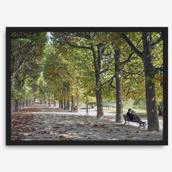 A fine art Paris print of Jardin des Tuileries in fall, featuring a couple sitting on a bench beneath vibrant autumn trees, surrounded by golden foliage.