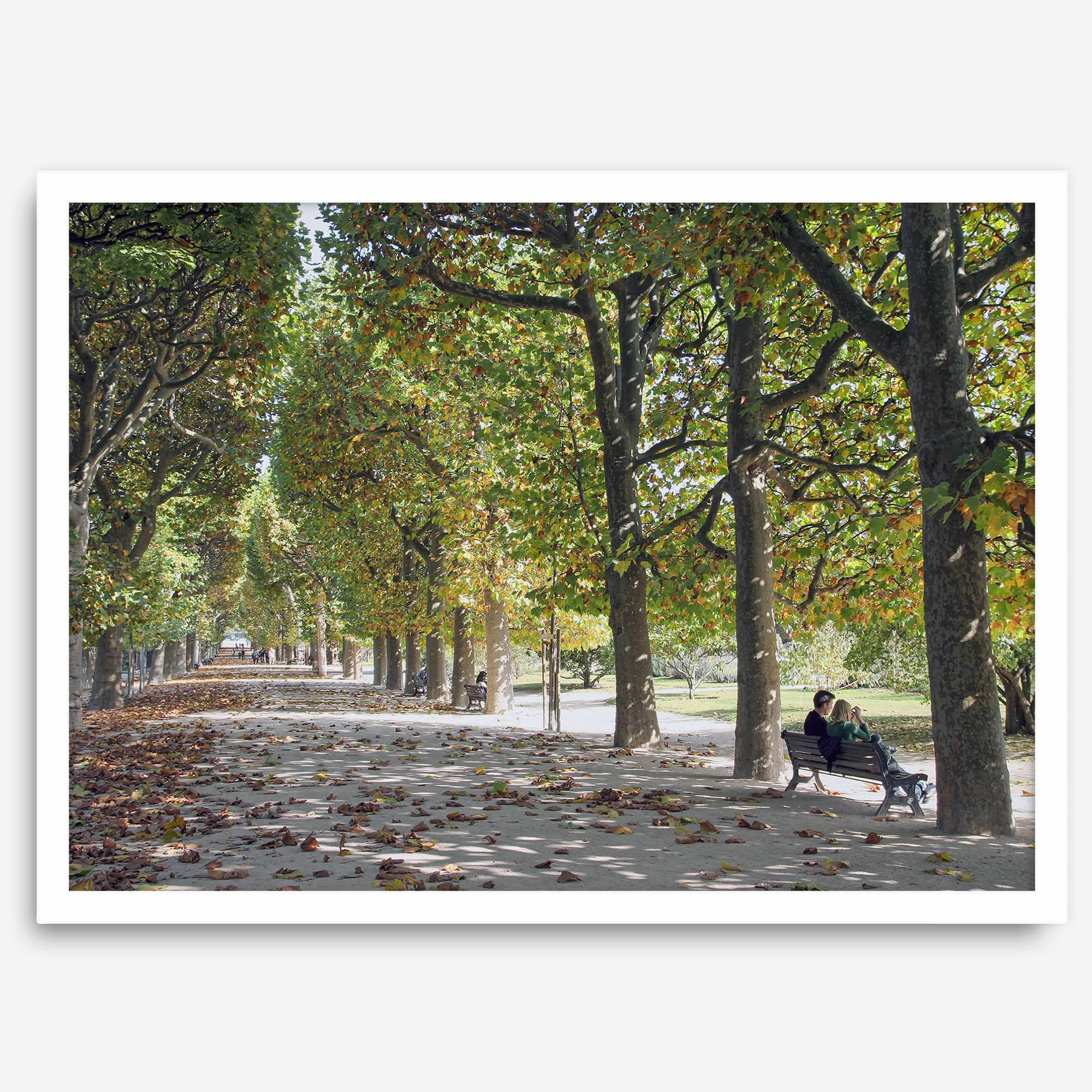 A fine art Paris print of Jardin des Tuileries in fall, featuring a couple sitting on a bench beneath vibrant autumn trees, surrounded by golden foliage.