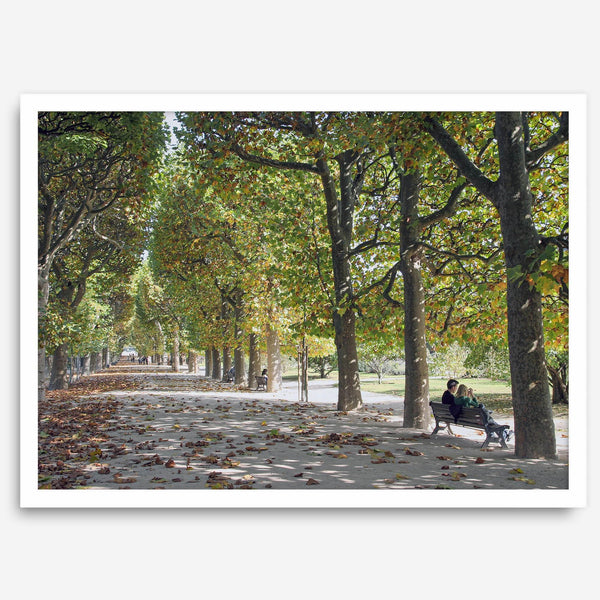A fine art Paris print of Jardin des Tuileries in fall, featuring a couple sitting on a bench beneath vibrant autumn trees, surrounded by golden foliage.
