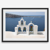 Santorini wall art featuring white church bell towers above the Aegean Sea in Santorini, Greece with volcanic cliffs and sailboats.