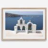 Santorini wall art featuring white church bell towers above the Aegean Sea in Santorini, Greece with volcanic cliffs and sailboats.