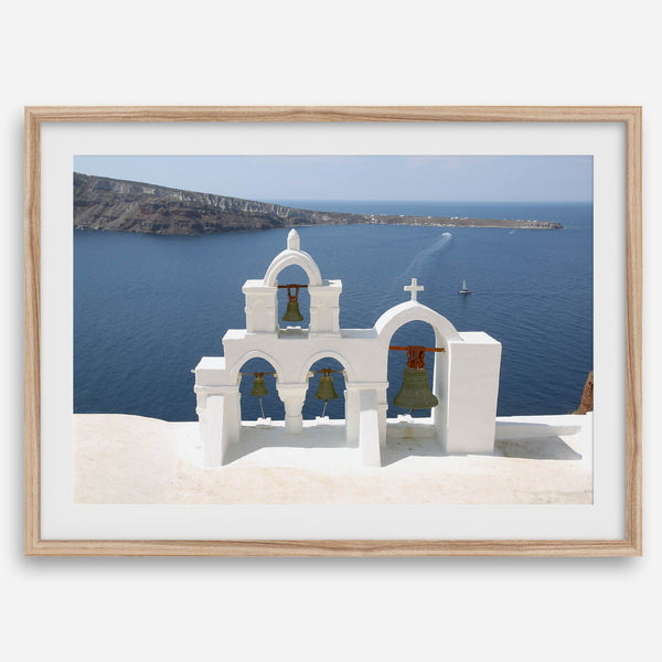 Santorini wall art featuring white church bell towers above the Aegean Sea in Santorini, Greece with volcanic cliffs and sailboats.
