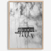 Monochrome ski lift view from below with hanging skis and cloudy mountain sky background.