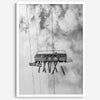 Monochrome ski lift view from below with hanging skis and cloudy mountain sky background.