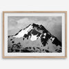 Black and white fine art photograph of a snowy Alaska mountain rising above coastal waters beneath dramatic clouds.