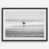 Black and white surfer photography showing a lone surfer on the beach, with waves in the background, capturing minimalist coastal beauty.
