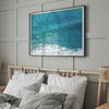Aerial beach wall art featuring a lone surfer paddling through turquoise ocean waves, with foamy white surf along the shoreline.