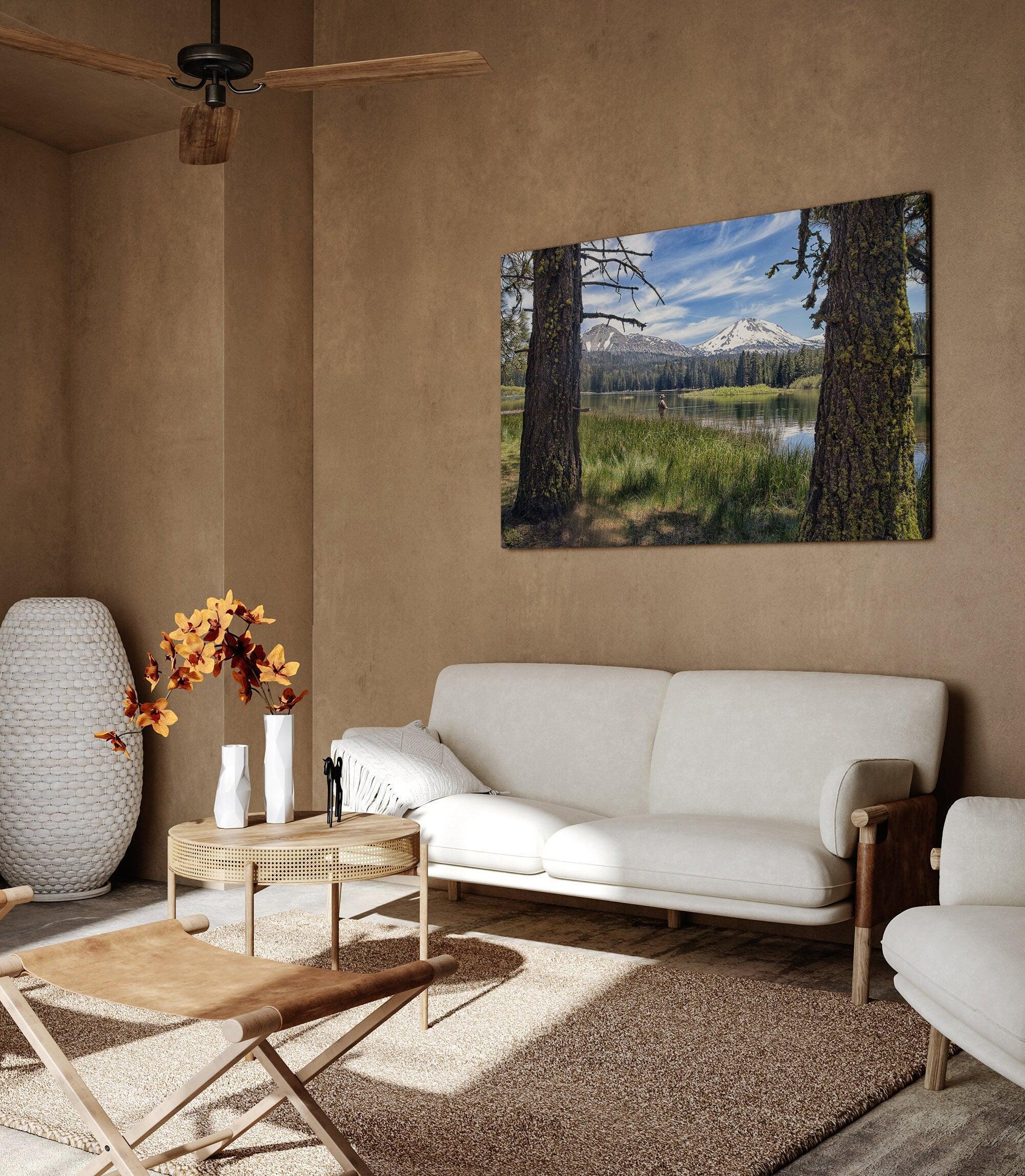 A stunning unframed or framed canvas print featuring a fisherman in Lassen National Park enjoying the tranquility of a serene lake nestled in the midst of towering snow-capped mountains.