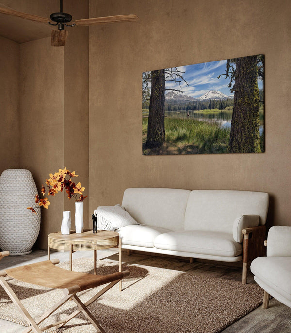 A stunning unframed or framed canvas print featuring a fisherman in Lassen National Park enjoying the tranquility of a serene lake nestled in the midst of towering snow-capped mountains.